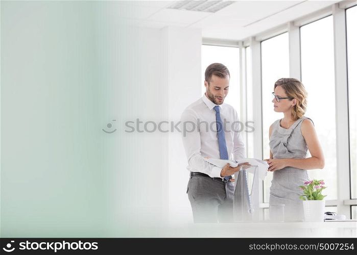 Businessman and businesswoman discussing over document at new office