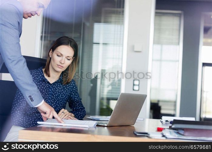 Businessman and businesswoman discussing over documents at desk in office