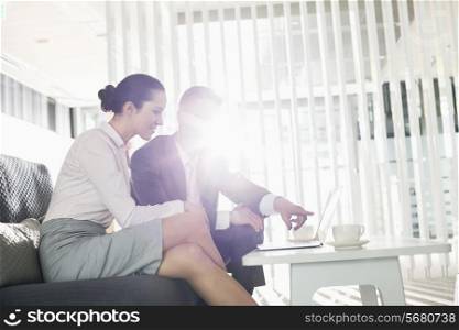 Businessman and businesswoman discussing over laptop in office