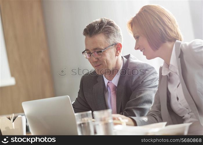 Businessman and businesswoman discussing while having lunch in office