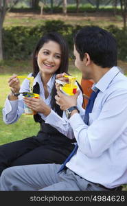 Businessman and businesswoman eating noodles