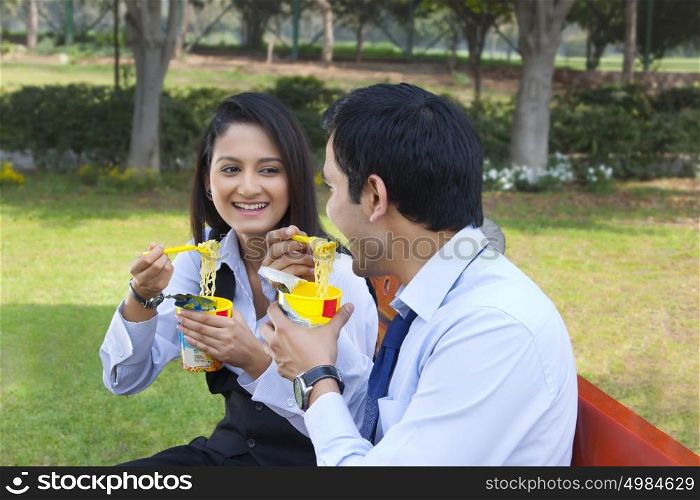 Businessman and businesswoman eating noodles