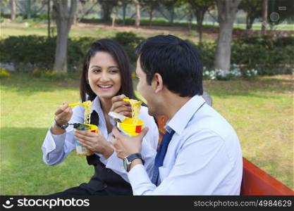 Businessman and businesswoman eating noodles