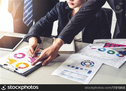 Businessman and businesswoman in meeting working with many financial statement document on desk. Concept of busy business profit analysis and brainstorm. Close up shot at people hands and papers.