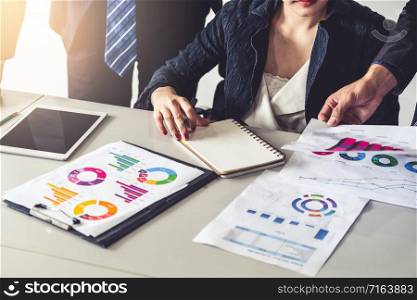 Businessman and businesswoman in meeting working with many financial statement document on desk. Concept of busy business profit analysis and brainstorm. Close up shot at people hands and papers.