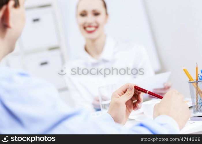 Businessman and businesswoman in office sitting at table and having conversation. Working in partnership