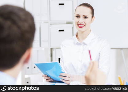 Businessman and businesswoman in office sitting at table and having conversation. Working in partnership