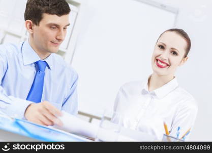 Businessman and businesswoman in office sitting at table and having conversation. Working in partnership