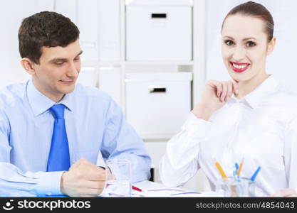 Businessman and businesswoman in office sitting at table and having conversation. Working in partnership