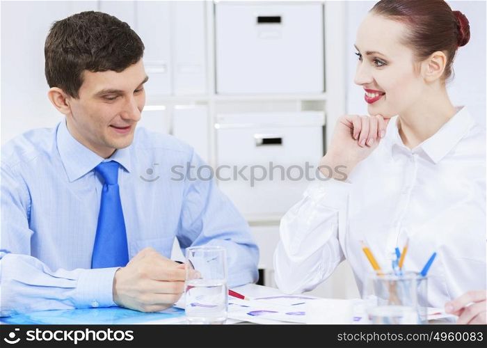 Businessman and businesswoman in office sitting at table and having conversation. Working in partnership