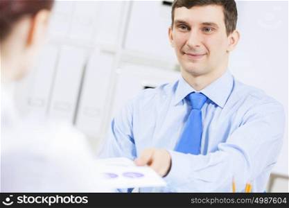 Businessman and businesswoman in office sitting at table and having conversation. Working in partnership