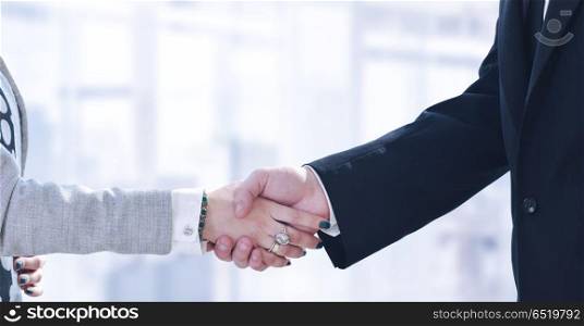Businessman and businesswoman shaking hands after meetup. Businessman and businesswoman shaking hands after meetup with modern office in background