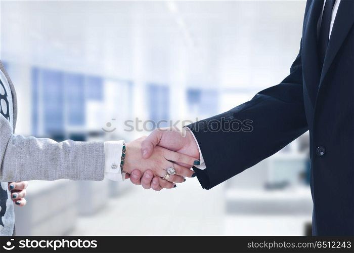 Businessman and businesswoman shaking hands after meetup with modern office in background. Businessman and businesswoman shaking hands after meetup