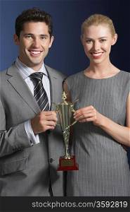 Businessman and Businesswoman Sharing Trophy