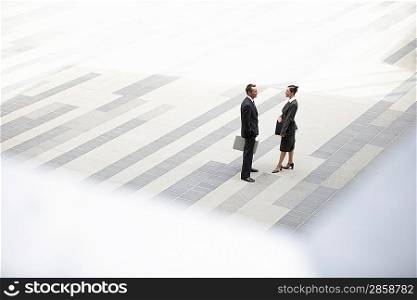 Businessman and businesswoman standing and talking in outdoor plaza elevated view