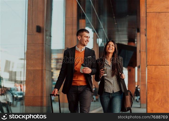 Businessman and businesswoman talking and holding luggage traveling on a business trip, carrying fresh coffee in their hands. Business concept. High-quality photo. Business man and business woman talking and holding luggage traveling on a business trip