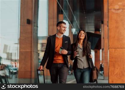 Businessman and businesswoman talking and holding luggage traveling on a business trip, carrying fresh coffee in their hands. Business concept. High-quality photo. Business man and business woman talking and holding luggage traveling on a business trip