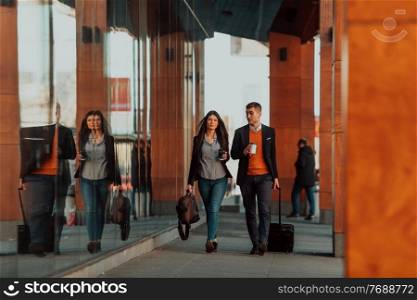 Businessman and businesswoman talking and holding luggage traveling on a business trip, carrying fresh coffee in their hands. Business concept. High-quality photo. Business man and business woman talking and holding luggage traveling on a business trip, carrying fresh coffee in their hands.Business concept