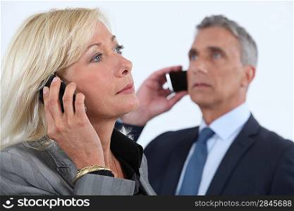 businessman and businesswoman talking on their cells