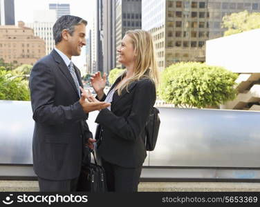 Businessman And Businesswoman Talking Outside Office