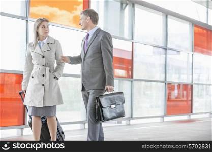 Businessman and businesswoman talking while walking on railroad platform