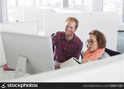 Businessman and businesswoman using computer in creative office