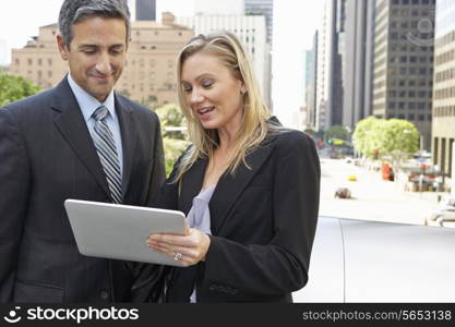 Businessman And Businesswoman Using Digital Tablet Outside