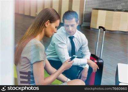 Businessman and businesswoman waiting for their car pick up in hotel lobby
