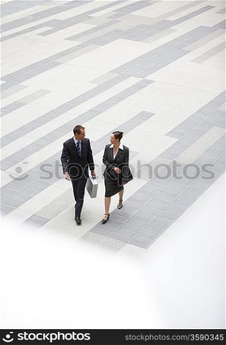Businessman and businesswoman walking across outdoor plaza elevated view