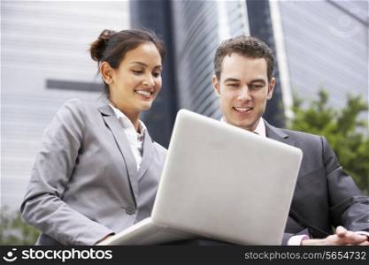 Businessman And Businesswoman Working On Laptop Outside Office