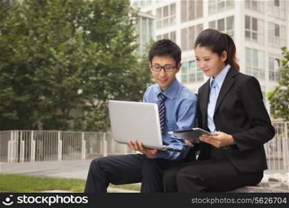 Businessman and businesswoman working outdoors