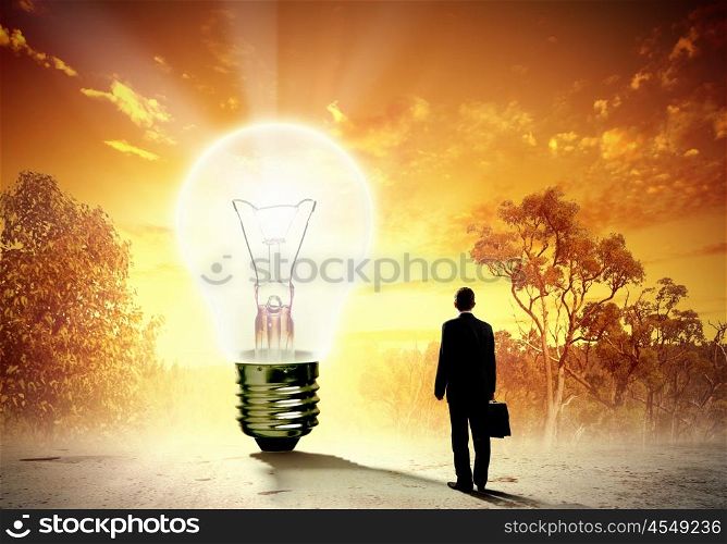 Businessman and ecology issue. Image of businessman looking at light bulb. Green energy concept