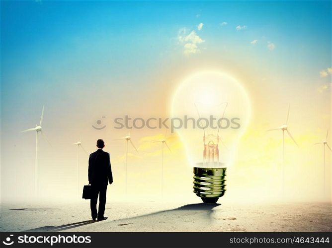 Businessman and ecology issue. Image of businessman looking at light bulb. Green energy concept