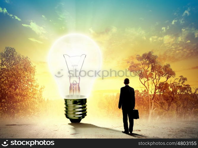 Businessman and ecology issue. Image of businessman looking at light bulb. Green energy concept