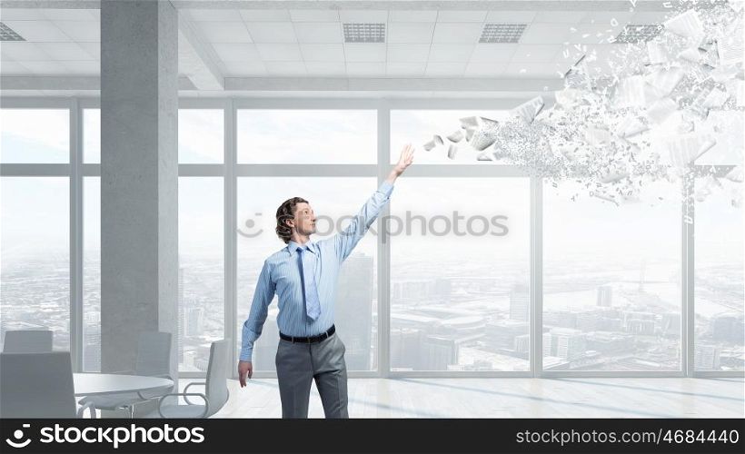 Businessman and flying papers mixed media. Young businessman throwing sheets of paper into the air