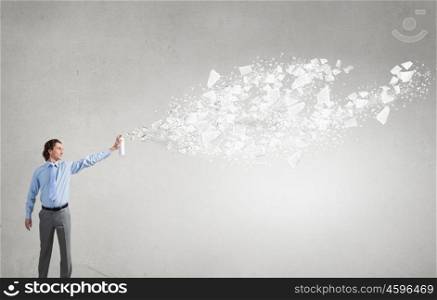 Businessman and flying papers. Young businessman spraying sheets of paper into the air