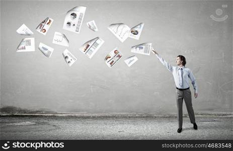 Businessman and flying papers. Young businessman throwing sheets of paper into the air