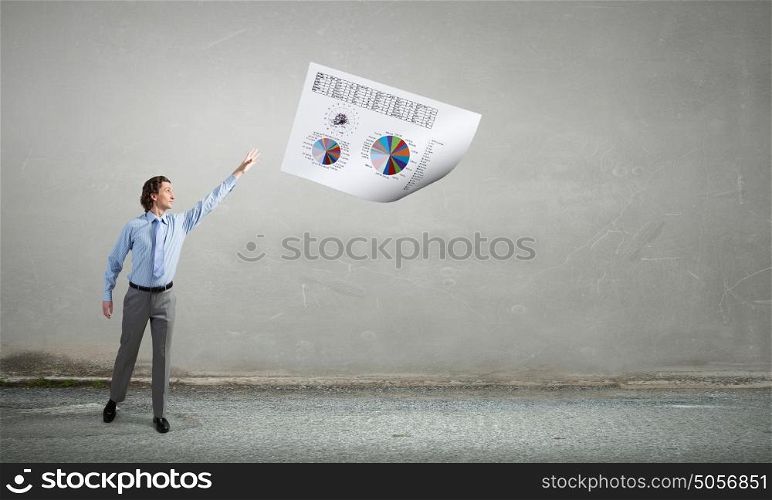 Businessman and flying papers. Young businessman throwing sheets of paper into the air
