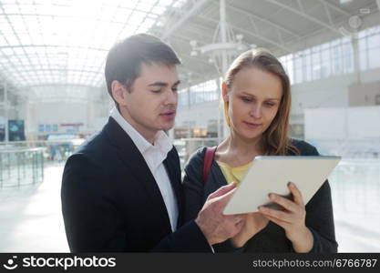 Businessman and his secretary talking on business using tablet computer. Man showing something on screen and giving instructions