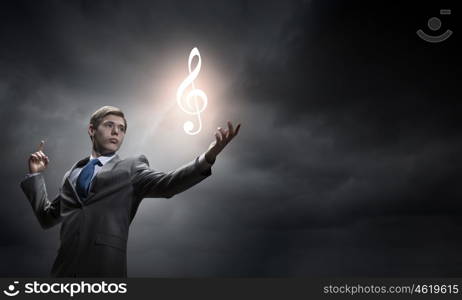 Businessman and music concept. Young man in suit holding music sign in palm