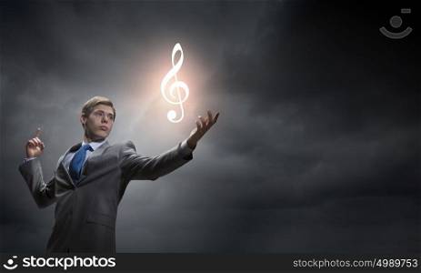 Businessman and music concept. Young man in suit holding music sign in palm
