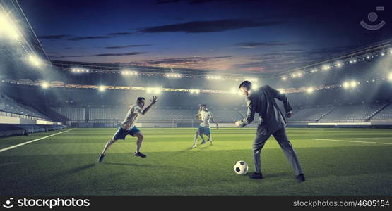 Businessman and player fighting for ball. Young businessman in suit playing football at stadium