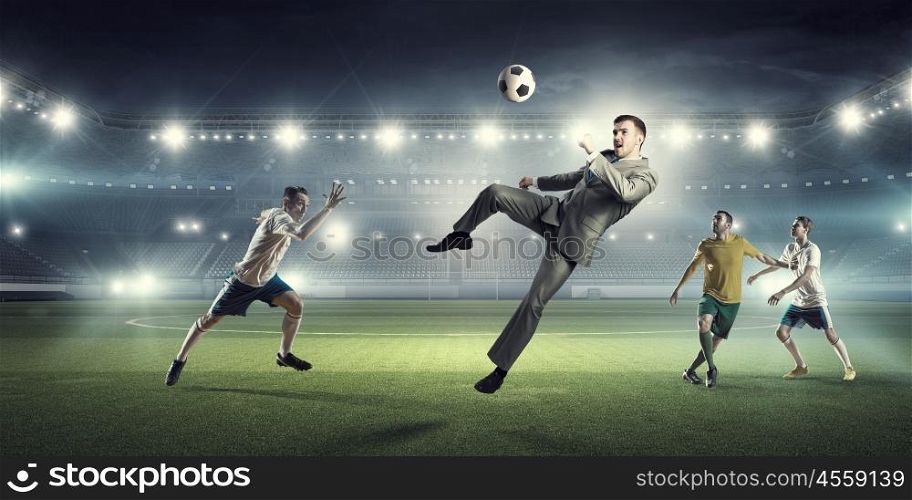 Businessman and players fighting for ball. Young businessman in suit playing football at stadium