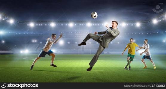 Businessman and players fighting for ball. Young businessman in suit playing football at stadium