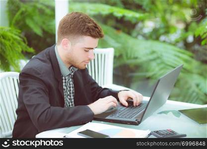 businessman and smiling, as he work on his laptop in the living room.
