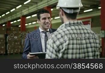 Businessman and supervisor in shipping facility talking to young man at work as manual worker, people working in warehouse, workers in industry. 3of19