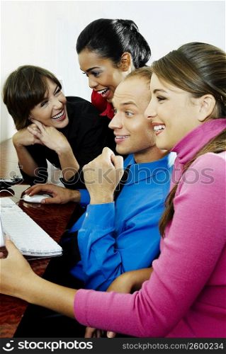 Businessman and three businesswomen sitting in front of computer and smiling