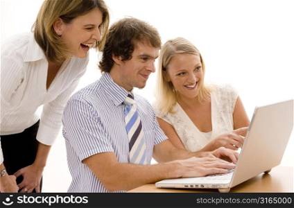 Businessman and two businesswomen looking at a laptop and smiling