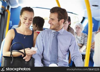 Businessman And Woman Looking At Mobile Phone On Bus
