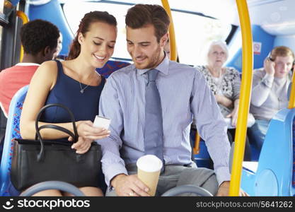 Businessman And Woman Looking At Mobile Phone On Bus